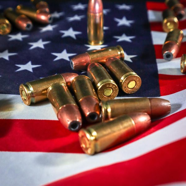 Close-up of ammunition bullets arranged on an American flag, symbolizing gun rights and control issues.